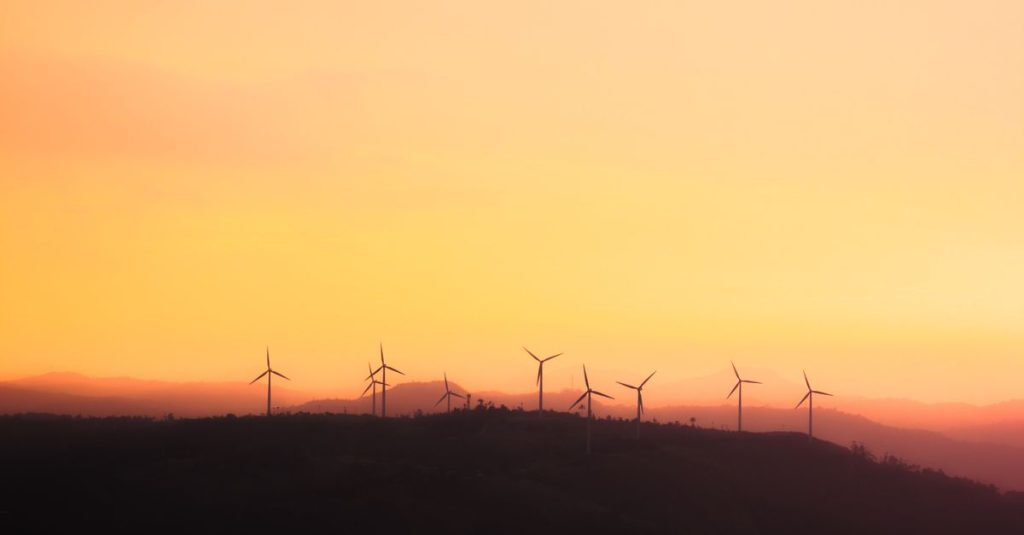 Silhouette of wind turbines at sunset, promoting sustainable energy.