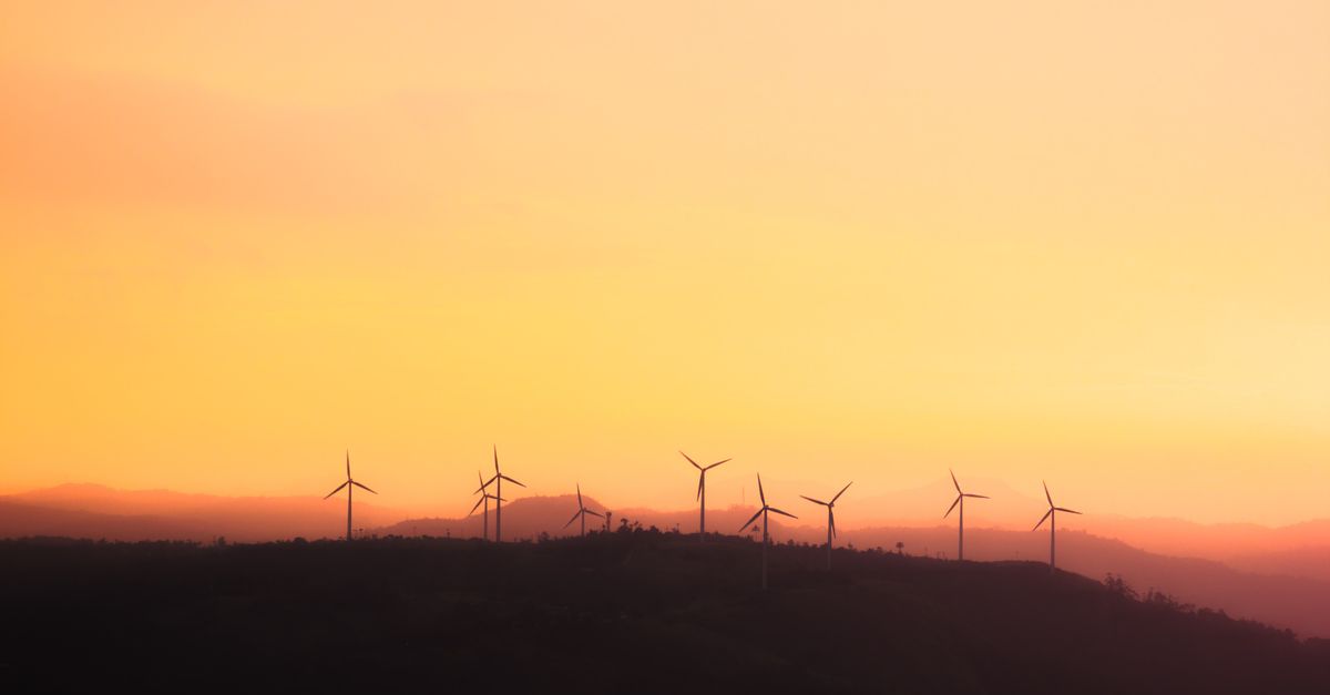 Silhouette of wind turbines at sunset, promoting sustainable energy.