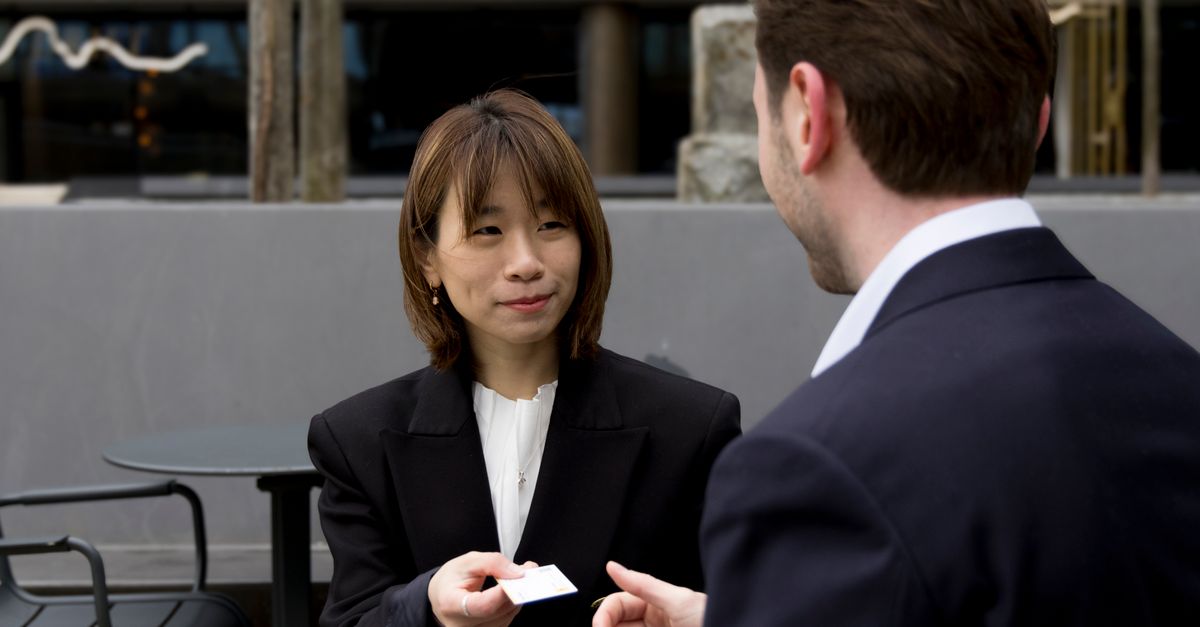 Two business professionals having a meeting outdoors, exchanging business cards.