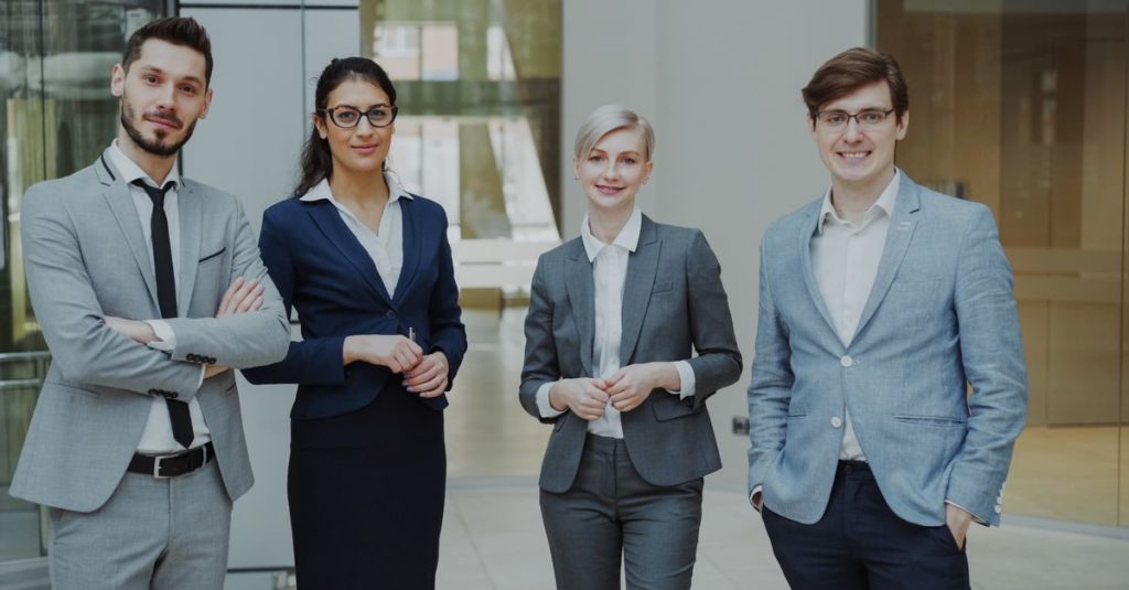 Four business professionals posing confidently in a modern office environment.