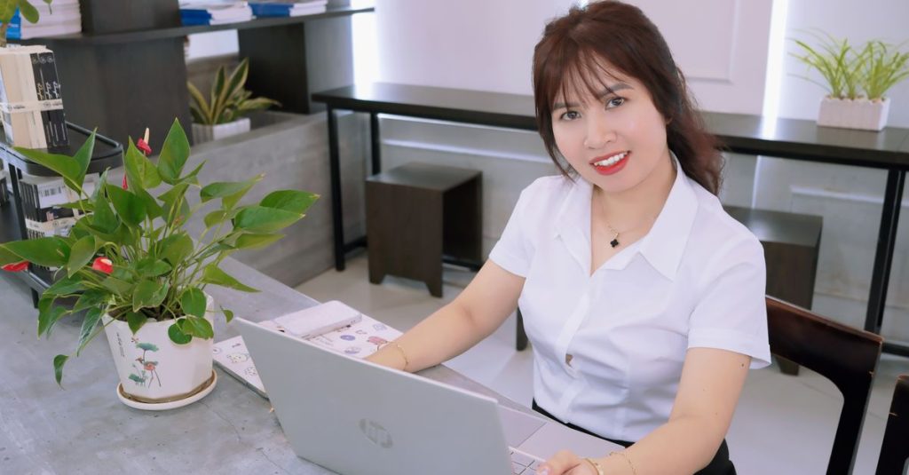 Người phụ nữ làm việc với máy tính xách tay trong không gian văn phòng sáng sủa, hiện đại.