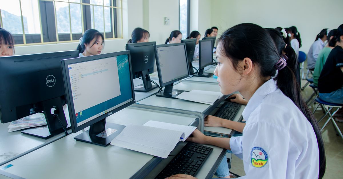 Group of Asian students working together in a computer lab focused on teamwork and technology.