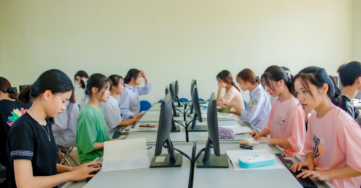 A group of students in a classroom using computers for team learning activities.