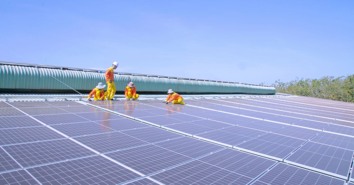 Team of workers installing solar panels on a large rooftop, promoting renewable energy and sustainability.