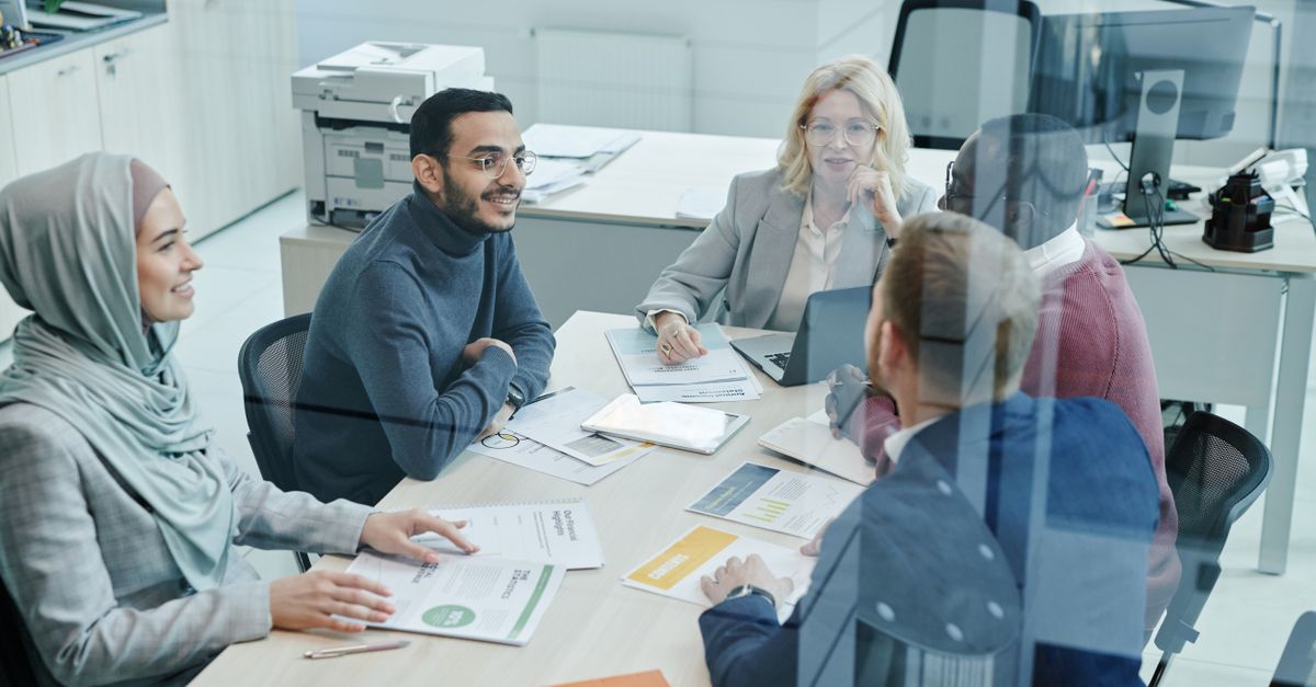 A diverse group of professionals engaged in a meeting at a modern office, promoting teamwork and collaboration.