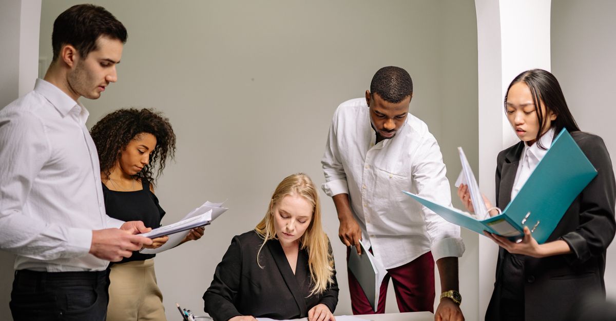Diverse team working together in an office setting, reviewing documents and collaborating on projects.