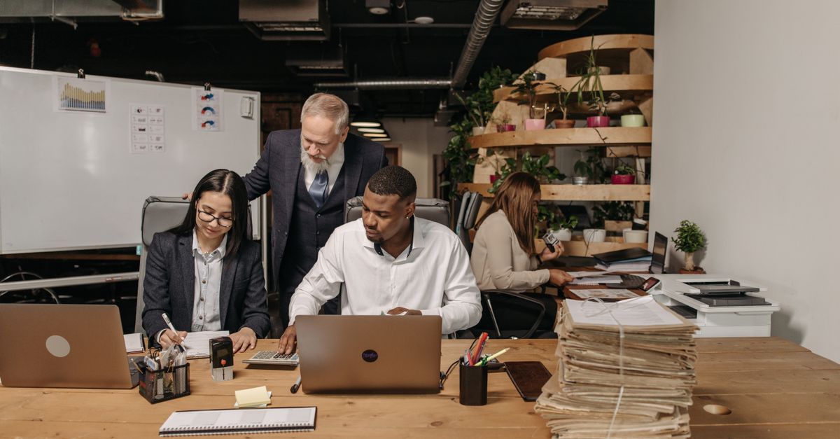Team of professionals working collaboratively in a modern office environment with documents and laptops.
