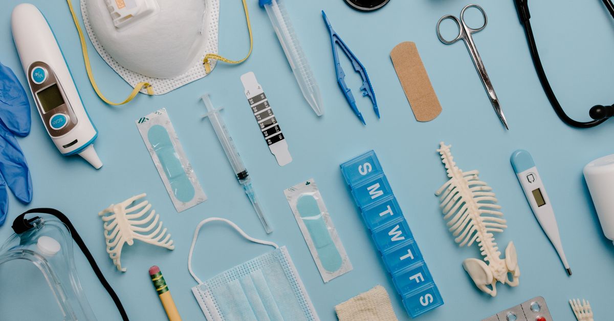 A comprehensive flat lay of diverse medical supplies including PPE and diagnostic equipment on a blue surface.