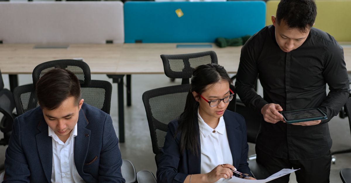 A professional team collaborating in a modern office setting, focusing on documents and technology.